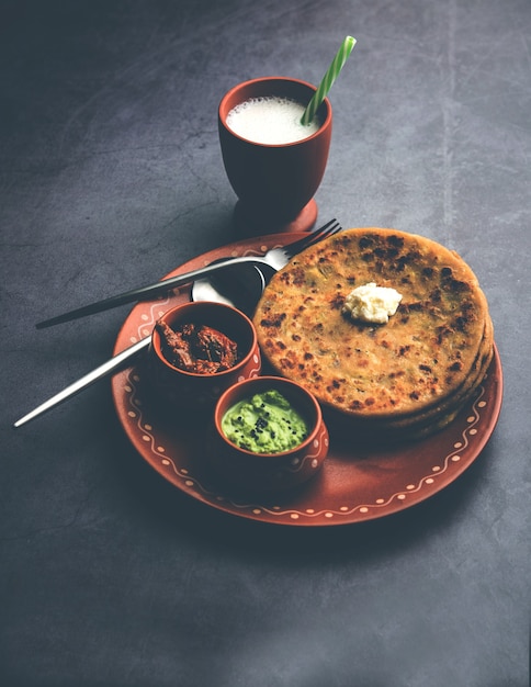 Aloo Paratha ou Batata Indiana recheada de pão achatado com manteiga por cima. Servido com Lassi doce fresco, chutney e picles. foco seletivo