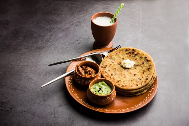 Aloo Paratha ou Batata Indiana recheada de pão achatado com manteiga por cima. Servido com Lassi doce fresco, chutney e picles. foco seletivo