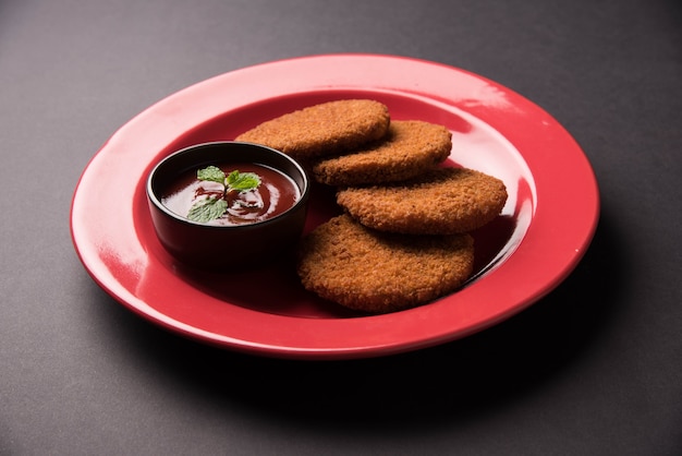 Aloo Tikki o Patties o Cutlet es un bocadillo o bocadillo popular de la India, servido con salsa de tomate o salsa picante Imli sobre un fondo de mal humor. Enfoque selectivo
