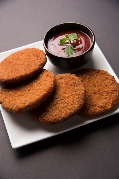 Aloo Tikki o Patties o Cutlet es un bocadillo o bocadillo popular de la India, servido con salsa de tomate o salsa picante Imli sobre un fondo de mal humor. Enfoque selectivo