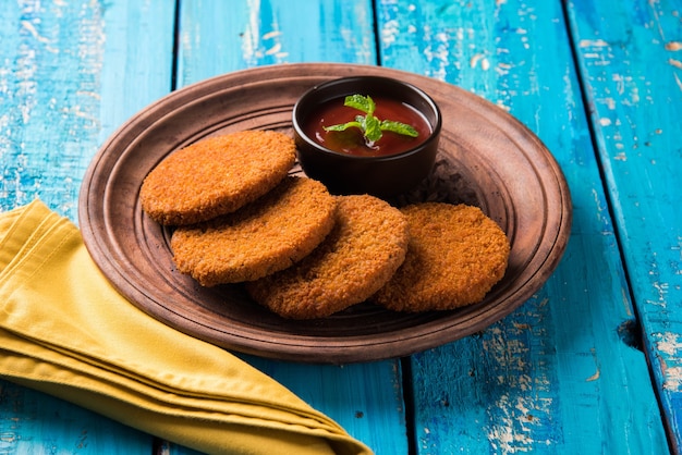 Aloo Tikki ou Patties or Costlet é um lanche popular ou lanche da Índia, servido com ketchup de tomate ou chutney de Imli sobre um fundo temperamental. Foco seletivo
