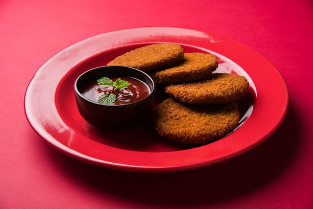 Aloo Tikki ou Patties or Costlet é um lanche popular ou lanche da Índia, servido com ketchup de tomate ou chutney de Imli sobre um fundo temperamental. Foco seletivo