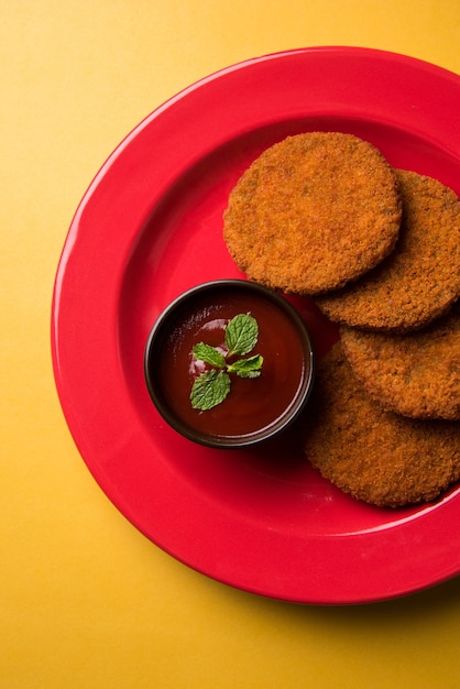 Aloo Tikki ou Patties or Costlet é um lanche popular ou lanche da Índia, servido com ketchup de tomate ou chutney de Imli sobre um fundo temperamental. Foco seletivo