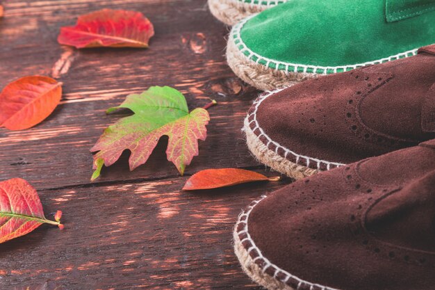 Alpargatas de ante marrón y verde para hombre en madera con hojas.