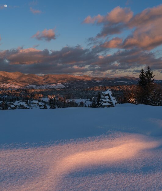 Alpendorf Stadtrand in letzten Abend Sonnenuntergang Sonnenlicht Winter schneebedeckte Hügel und Tannen Stichbild mit hoher Auflösung und großer Schärfentiefe