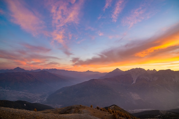 Los Alpes franceses italianos al atardecer. Cielo colorido sobre los majestuosos picos de las montañas, terreno seco y árido y valles verdes.