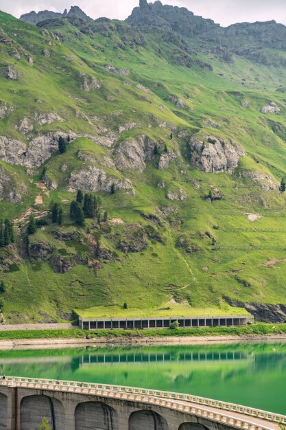 Alpes lindos com colina verde e represa no rio