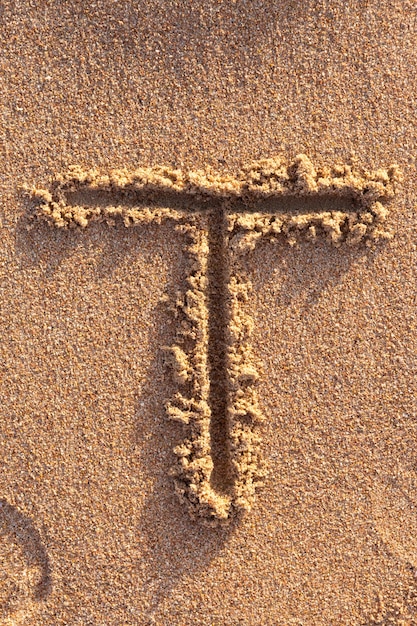 Alphabet (T) Buchstaben handgeschrieben in Sand am Strand