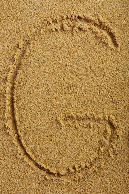 Alphabetbuchstabe geschrieben auf nassem Strandsand