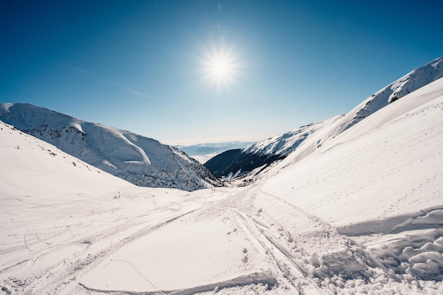 Alpine Berglandschaft mit weißem Schnee und blauem Himmel Sonnenuntergang Winter in der Natur Frostige Bäume unter warmem Sonnenlicht Wunderbare Winterlandschaft