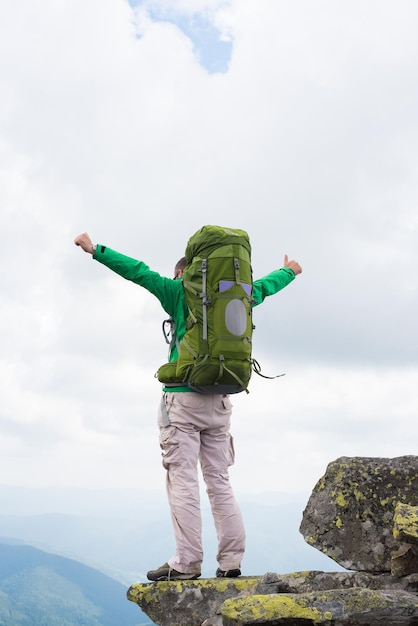 Alpinista com mochila em cima de uma montanha Thumbsup