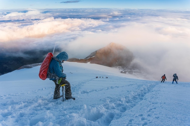 Alpinista com mochilas atinge o cume do pico da montanha