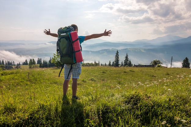 Alpinista com uma mochila em pé nas montanhas