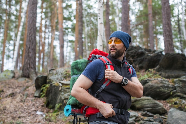 Alpinista com uma mochila na floresta fecha o retrato