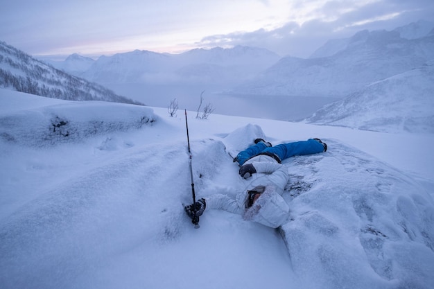 Alpinista de homem adoecendo no topo da colina de neve