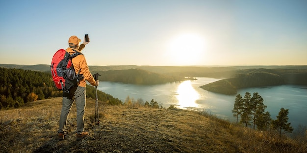 Alpinista de homem tomando selfie por smartphone nas montanhas ao pôr do sol Conceito de viagem e estilo de vida ativo Banner com espaço de cópia