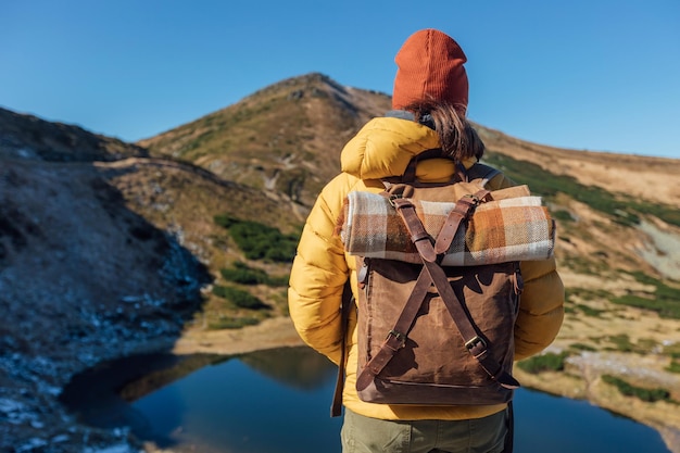 Alpinista de jaqueta amarela com mochila vintage turista com mochila caminhando montanhas em co