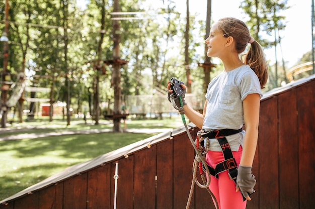 Alpinista de menina no parque de corda, playground. criança escalando ponte suspensa