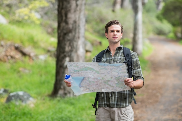 Alpinista de pé com mapa na trilha na floresta