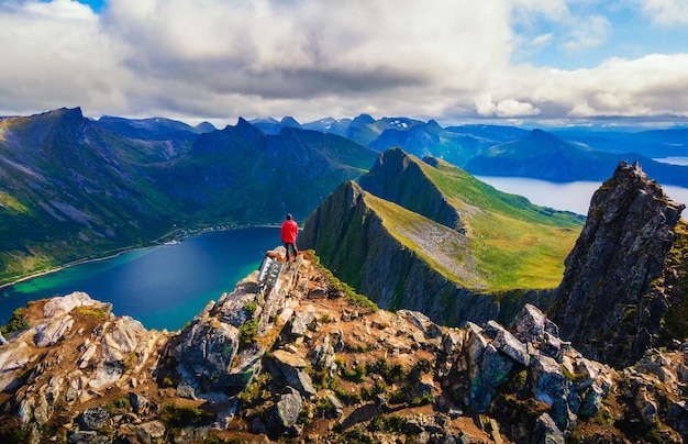 Alpinista de pé no topo da Montanha Husfjellet na Ilha Senja na Noruega