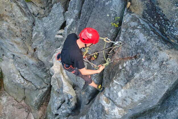 Alpinista determinado escalando parede íngreme de uma montanha rochosa. esportista superando rota difícil. envolvendo-se em esportes radicais e conceito de passatempo de escalada em rocha.