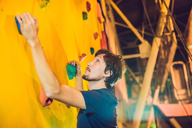 Alpinista em parede de escalada artificial em ginásio de boulder