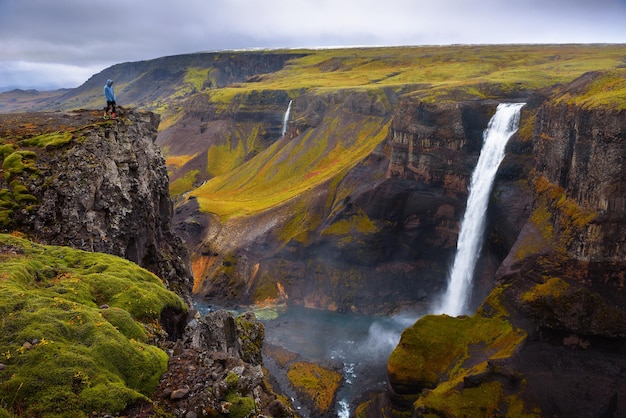 Alpinista em pé na beira da cachoeira Haifoss na Islândia