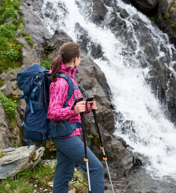 Alpinista em roupa moderna perto de cachoeira