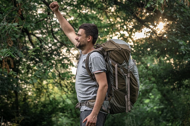 Alpinista em uma caminhada com uma grande mochila em um fundo desfocado da floresta.