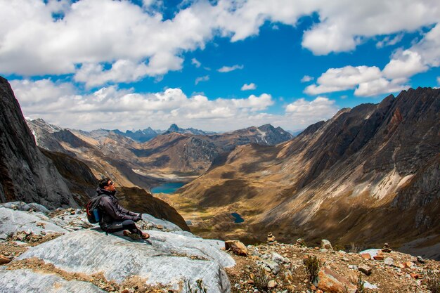 Alpinista em uma montanha nos Andes peruanos ao fundo um belo lago e céu azul