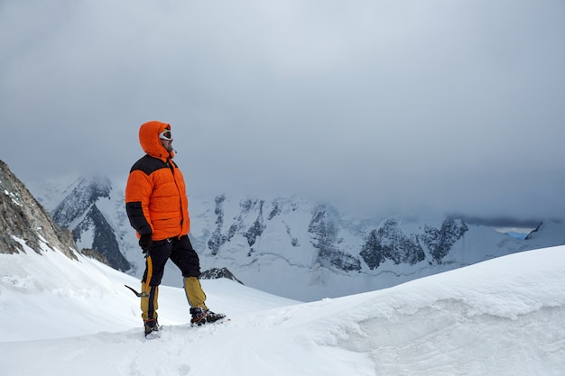 Alpinista escalador se encuentra en la cima de la montaña. Picos nevados y cielo, Altai, Belukha