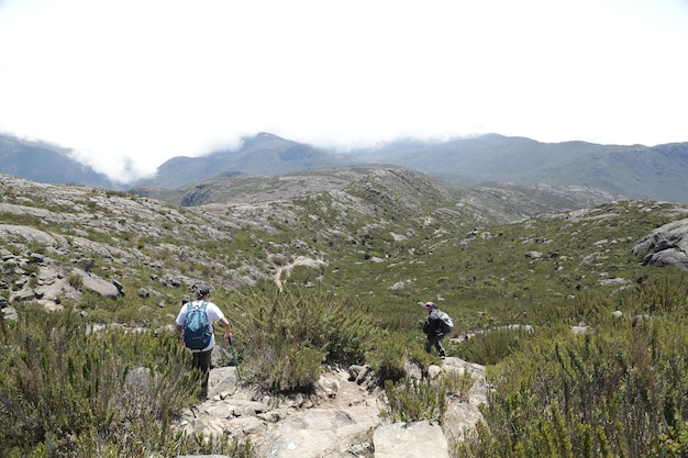 Alpinista escalando os picos mais altos do brasil nas montanhas com extensa caminhada e mochila.