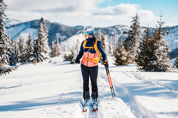 Alpinista esquí de travesía caminar esquí mujer alpinista en las montañas Esquí de travesía en paisaje alpino con árboles nevados Aventura deporte de invierno Esquí freeride