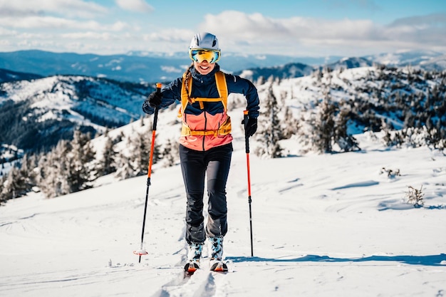 Alpinista esquí de travesía caminar esquí mujer alpinista en las montañas Esquí de travesía en paisaje alpino con árboles nevados Aventura deporte de invierno Esquí freeride