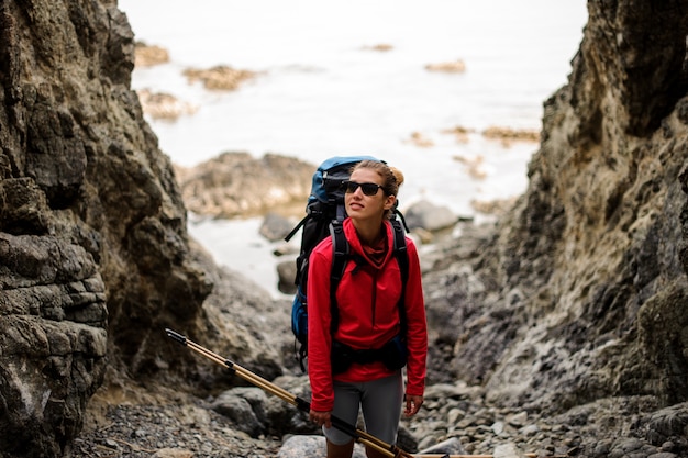 Alpinista feminina com mochila fica entre falésias