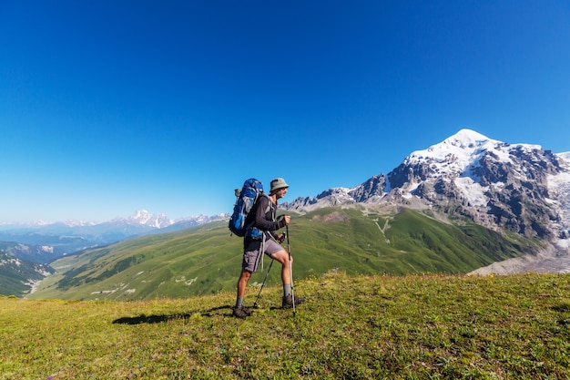 Alpinista indo ao longo de colinas verdes nas montanhas do Cáucaso, Svaneti, Geórgia. Temporada de verão.
