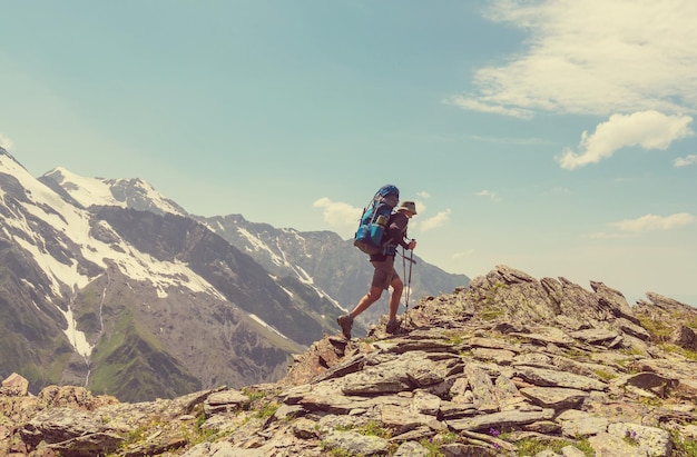 Alpinista indo ao longo de colinas verdes nas montanhas do Cáucaso, Svaneti, Geórgia. Temporada de verão.