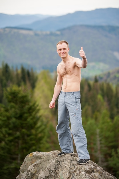 Alpinista masculina com mochila marrom no pico da rocha