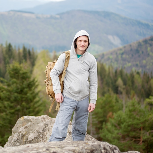 Alpinista masculina com mochila marrom no pico da rocha