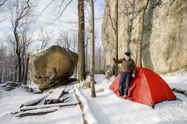 Alpinista masculina quase sua tenda vermelha nas montanhas