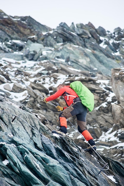 Alpinista masculino escalando a montanha rochosa