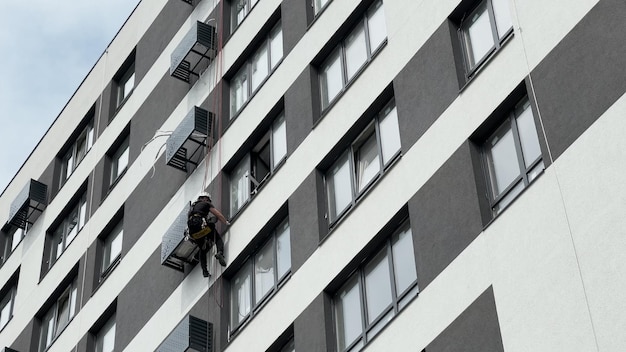 Alpinista profissional instala uma unidade externa de ar condicionado em uma casa Instala ou repara o ar condicionado