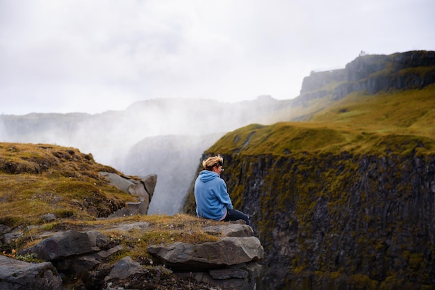 Alpinista sentado à beira da cachoeira gullfoss na islândia