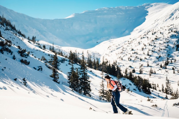 Alpinista sertão esqui andando alpinista nas montanhas Esqui de turismo na paisagem alpina com árvores nevadas Esporte de inverno de aventura