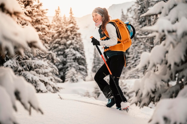 Alpinista sertão esqui andando alpinista nas montanhas Esqui de turismo na paisagem alpina com árvores nevadas Esporte de inverno de aventura