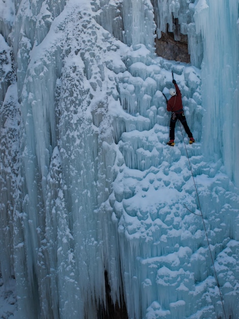 Alpinista subindo uma cachoeira congelada no parque de gelo, Ouray.