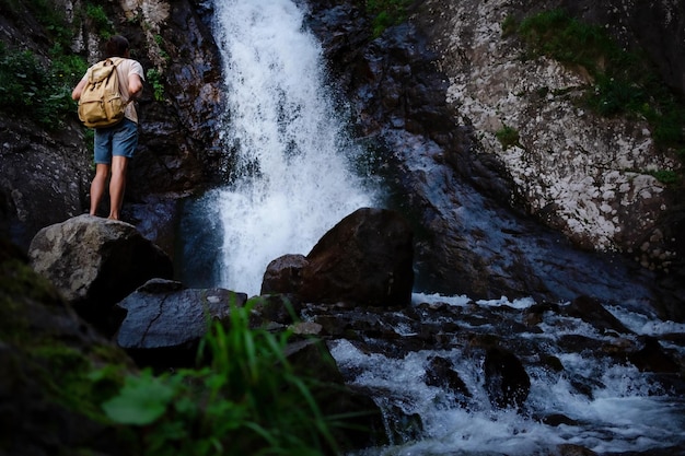 Alpinista waalkinh com mochila olhando para cachoeira no parque na bela paisagem natural