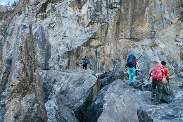 Alpinistas preparando-se para a subida Três pessoas masculinas e femininas caminhando nas rochas Esporte extremo ao ar livre