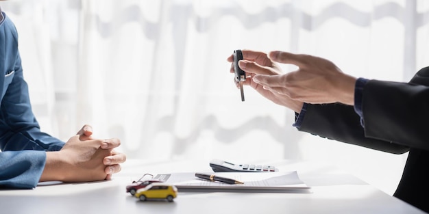 Alquiler de coches y concepto de seguro El vendedor joven que da el coche es clave para el cliente después de firmar un contrato de acuerdo con la aprobación para el alquiler o la compra