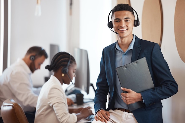 Als Führungskraft halte ich mein Team immer auf Kurs Porträt eines jungen Callcenter-Agenten mit einem Ordner in einem Büro, im Hintergrund seine Kollegen